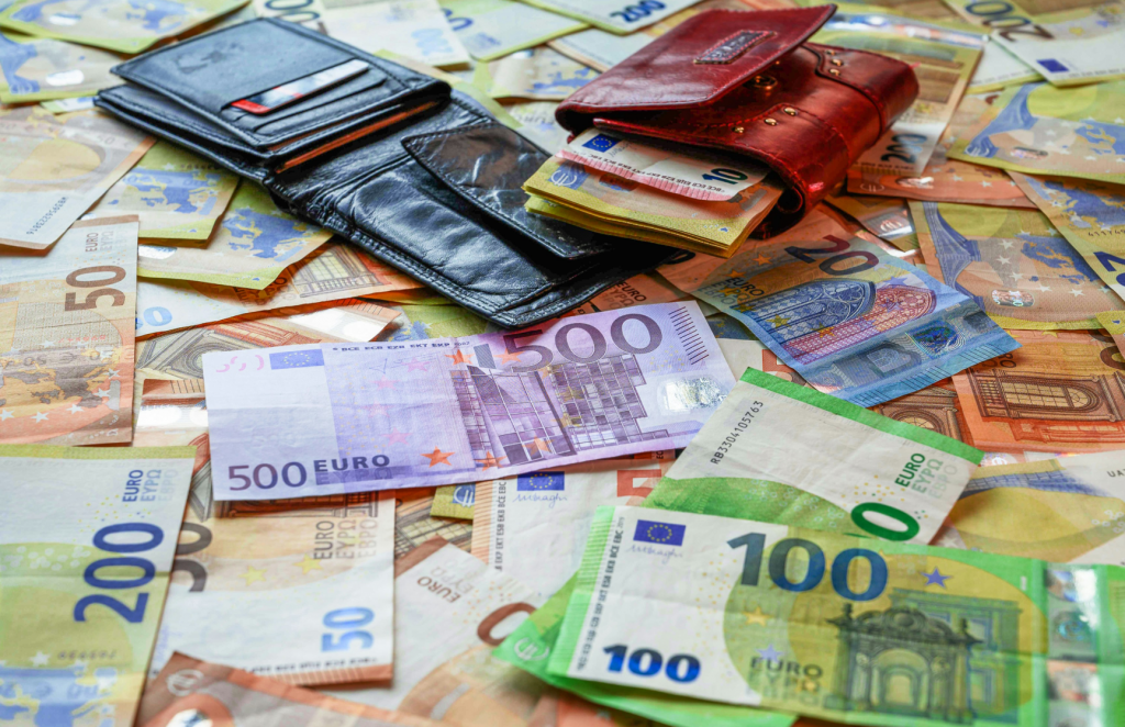 Euro-Geldscheine in verschiedenen Werten und zwei Geldbörsen, die auf einer Oberfläche verstreut sind. Symbolisiert finanzielle Vorteile und Steuervorteile bei Kapitalanlagen in Immobilien.